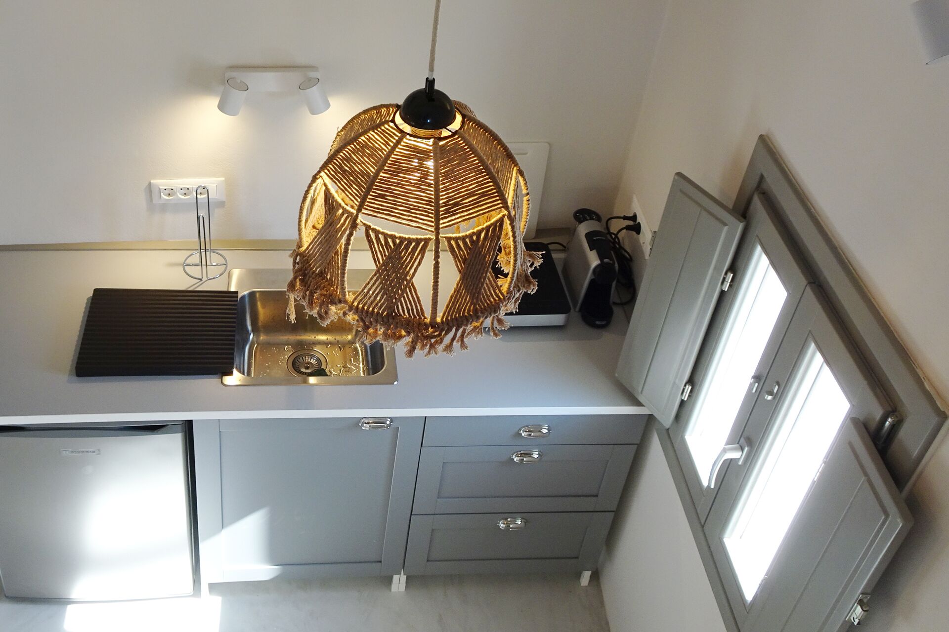 Une cuisine équipée d’un évier, d’un four à micro-ondes et d’un luminaire suspendu en macramé.