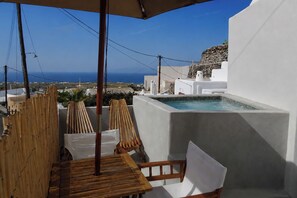 Eine Dachterrasse mit Pool, Holzmöbeln und Blick aufs Meer.