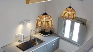 Cozinha com design moderno, apresentando uma pia de aço inoxidável, luminária pendente de madeira e uma janela com vista.