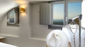 Quarto com uma janela grande, guarda-roupa e um cabideiro com um chapéu.