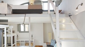 Um loft espaçoso com pé direito alto, escada e mezanino.