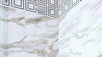 A shower with a marble wall and a geometric pattern above the showerhead.