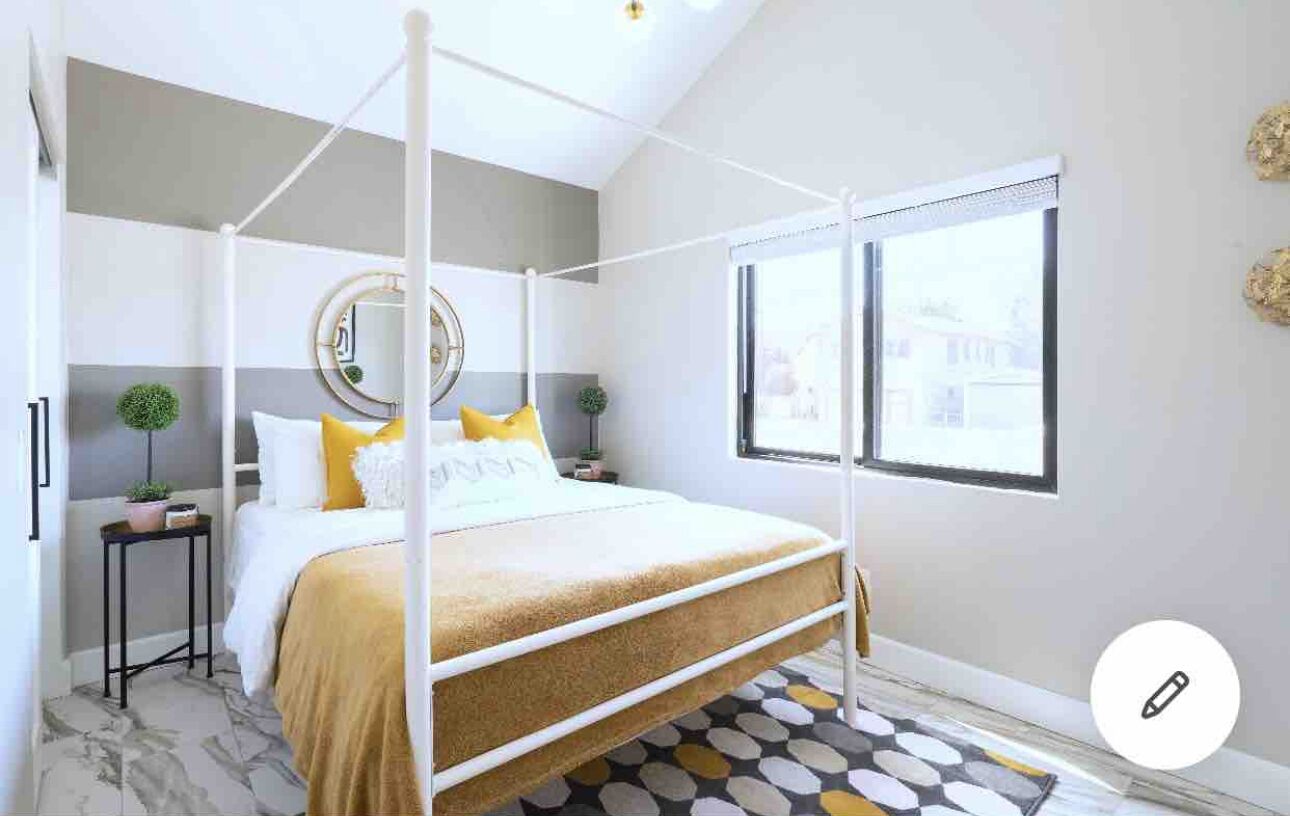 Un dormitorio moderno con cama con dosel, un ventanal y vistas de la ciudad.