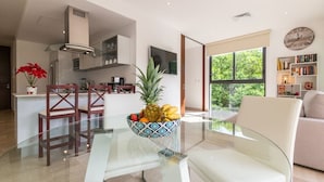 A modern kitchen with a glass dining table, a fruit bowl, and a view of the outdoors. - Mexication Beach Bliss: Stylish Playa Getaway (Playa del Carmen)