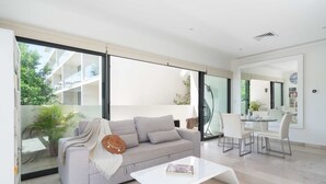A modern living room with a sofa, coffee table, and dining area. - Mexication Beach Bliss: Stylish Playa Getaway (Playa del Carmen)