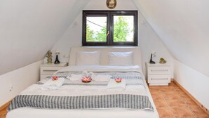 Une chambre à coucher avec un lit, deux tables de chevet, une fenêtre et une poutre au plafond.