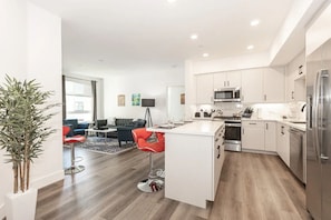 A modern kitchen with white cabinets, stainless steel appliances, and a central island.