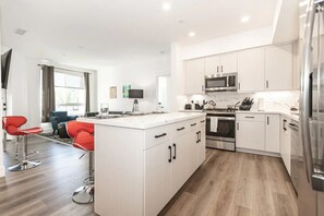 A modern kitchen with white cabinets, stainless steel appliances, and a central island. - Beach Condo 436CB (Carlsbad)