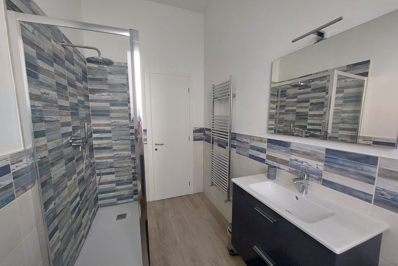 A modern bathroom with a shower, a sink, and a mirror.