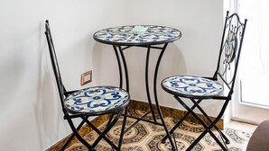Due tavoli rotondi con sedie, ognuno con un piano in legno decorato con un motivo blu e bianco.