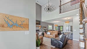 A spacious living room with a large wooden map, a leather sofa, and a dining area with a kitchen in the background. - Our Sweet Little Piece of Tennessee  (Estill Springs)