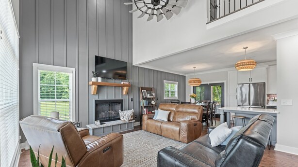A spacious living room with leather sofas, a fireplace, and a modern kitchen in the background. - Our Sweet Little Piece of Tennessee  (Estill Springs)
