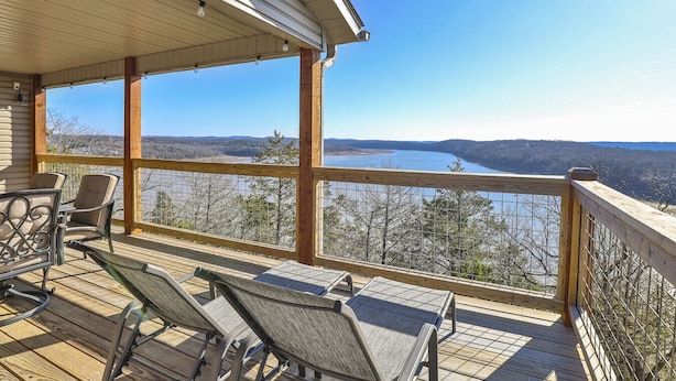 Una terraza de madera con asientos exteriores y vistas a un lago y montañas.