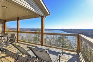 Eine Holzterrasse mit Sitzgelegenheiten und Blick auf einen See und Berge.