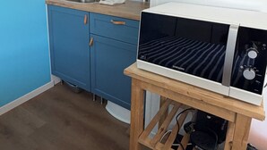 Eine Küche mit einer Mikrowelle auf einem Holzboden, einem Spülbecken und einem blauen Schrank.