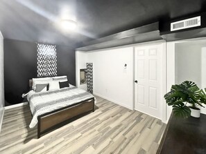 A bedroom with a bed, a wardrobe, a mirror, and a potted plant.