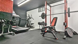 Ein Fitnessstudio mit Krafttrainingsgeräten, Laufbändern und einem roten Stuhl.