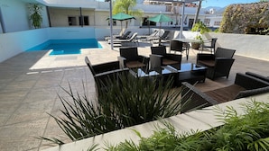 A rooftop pool area with lounge chairs and a table, surrounded by potted plants. - H.Ixaya (Puerto Vallarta)
