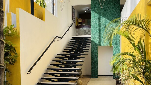 A modern staircase with a black handrail and geometric design, leading to a room with a green wall and a white ceiling. - H.Ixaya (Puerto Vallarta)
