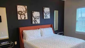 Quarto com cama, ventoinha no teto, obra de arte na parede e janela.