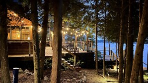 A wooden deck with string lights, a wooden cabin, and a view of the water.