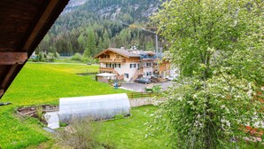 Una cabaña de montaña con fachada de madera, un invernadero y vistas a una cordillera.