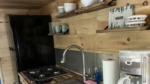 A compact kitchen with a wooden countertop, a gas stove, a sink, and a coffee maker. - Lavender Haze Cottage in the Woods (Oakland)
