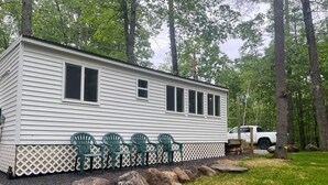A mobile home with a white exterior, green chairs outside, and a white truck parked nearby. - Lavender Haze Cottage in the Woods (Oakland)