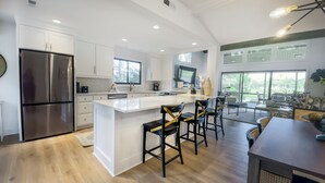 A modern kitchen with a large island, stainless steel appliances, and a dining area with bar stools. - 6960 Fairway One at The Sea Pines Resort (Hilton Head Island)