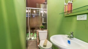 A bathroom with a glass shower enclosure, a white sink, and green walls. - Studio Apt. 316/fee Cleaning Free! (Medellín)