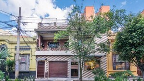 A two-story residential building with a balcony, a garage, and a small garden area. - Studio Apt. 316/fee Cleaning Free! (Medellín)