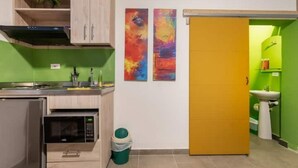 A compact kitchen with a microwave, cabinets, and a green trash bin. - Studio Apt. 316/fee Cleaning Free! (Medellín)