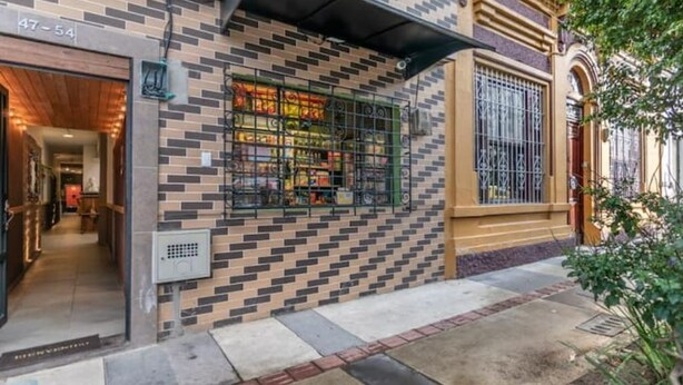 A building with a patterned facade, a storefront with a metal gate, and a visible door number. - Studio Apt. 316/fee Cleaning Free! (Medellín)