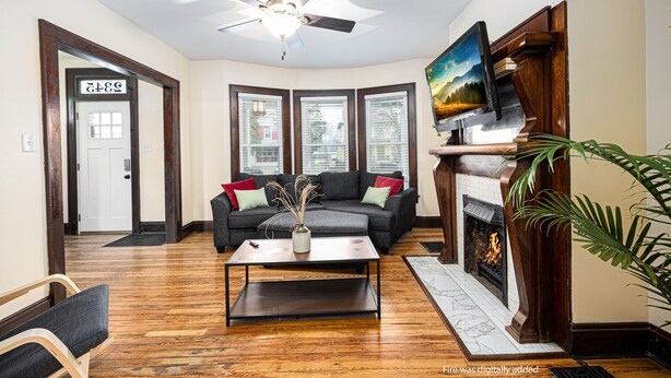A living room with a fireplace, a ceiling fan, a sofa, and a coffee table. - Spacious 4BD 2BA Home Near OSU (Columbus)