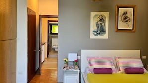 A bedroom with a bed, bedside table, and artwork on the wall. - Bnbook Casa Luccio Vista lago-Ispra (ISPRA)