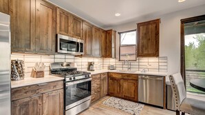 A modern kitchen with wooden cabinets, stainless steel appliances, and a large window. - Blue River Flats in Silverthorne, amazing location and panoramic mountain views (Silverthorne)