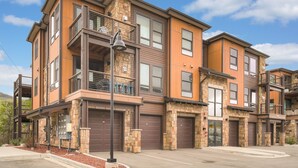A multi-story residential building with a stone facade, large windows, and a balcony. - Blue River Flats in Silverthorne, amazing location and panoramic mountain views (Silverthorne)