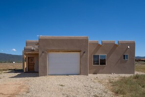 A modern house with a large garage door, a small window, and a door with a number sign.