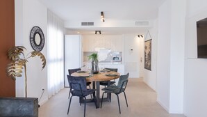 A modern dining area with a round table, four chairs, a vase, and a potted plant.