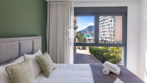 A hotel room with a bed, a view of a cityscape, and a balcony.