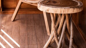 A wooden cabin interior with a cushioned chair and a round wooden table.