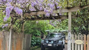 A black off-road vehicle parked at the entrance of a property with a wooden gate and a sign reading "Jacob's Cottage."