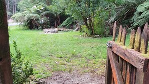 A stone pathway leading through a lush garden with a wooden fence on one side.