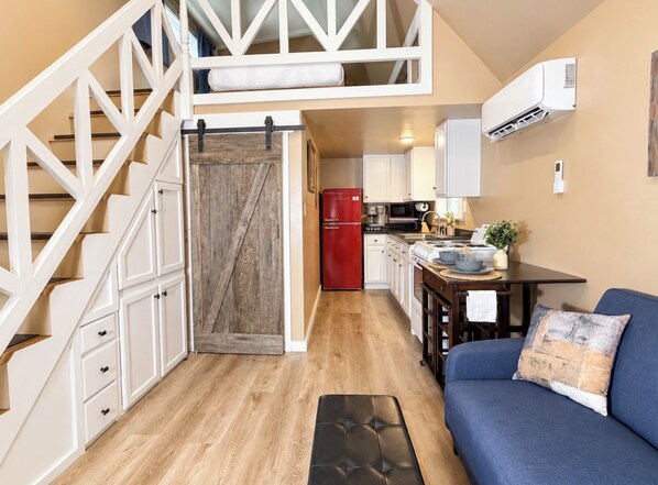 A compact kitchen with a red refrigerator, a dining table with a plant, and a blue sofa with a cushion. - Hemlock Cabin at Ranger Creek - Near Coalmont OHV Park! (Coalmont)
