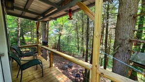 A wooden deck with a railing overlooking a forested area.