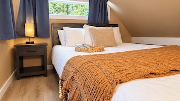Une chambre à coucher avec un lit, une table de chevet avec une lampe et une fenêtre avec des rideaux.