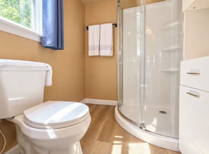 A modern bathroom with a toilet, a glass shower enclosure, and a white cabinet. - Oak Cabin at Ranger Creek - Near Coalmont OHV Park! (Coalmont)