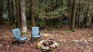 Een bos met twee metalen stoelen en een vuurkuil van steen.