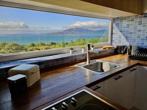 A kitchen with a view of the sea and mountains, a sink, a stove, and a window with a view. - Restored fisherhouse for 6 persons (Lira (Santa Maria))