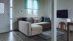 A living room with a sofa, a television, and a window with a curtain. - Restored fisherhouse for 6 persons (Lira (Santa Maria))